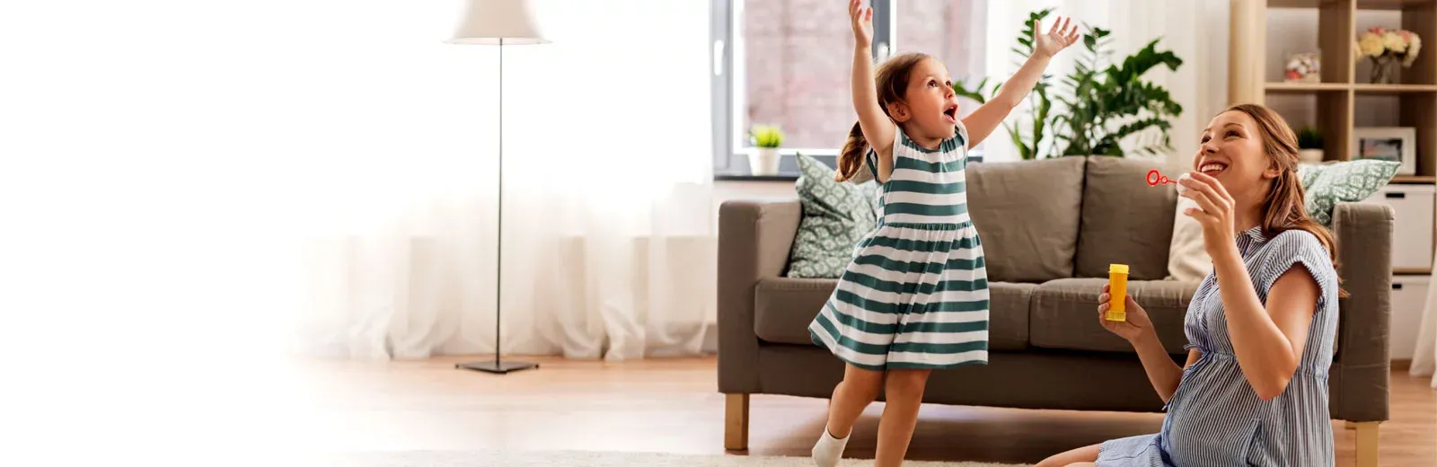 Mother and daughter blowing bubbles inside home